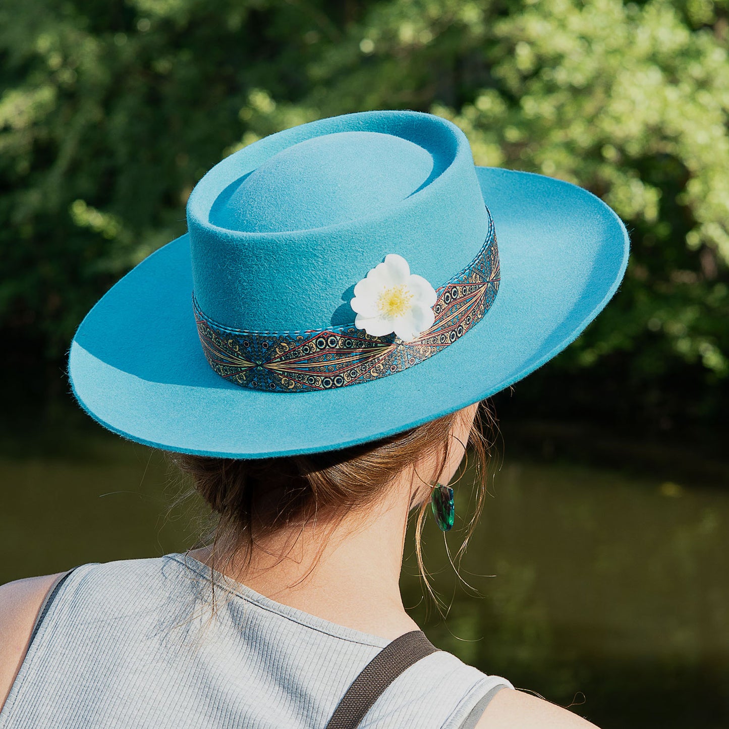 Turquoise Fedora viewed from the back with a white flower.
